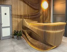 an office lobby with a curved wooden counter and potted plants on the side wall