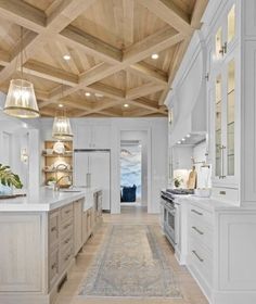 a large kitchen with white cabinets and wood ceilinging, along with an area rug on the floor