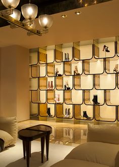 a living room filled with lots of furniture and shelves full of shoes on display behind glass doors