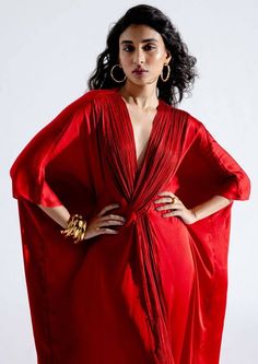 Introducing our regal red kaftan in luxurious modal satin, a versatile and striking piece that effortlessly adapts to any occasion. With a beautifully ruched v-neckline and a flowing kaftan silhouette, this garment in bold red is the perfect choice to dress up or down, making it suitable for a wide range of settings. Chic Silk V-neck Kaftan, Elegant Draped Kaftan With Draped Sleeves, Festive V-neck Satin Dresses, Elegant Festive Kaftan With Draped Sleeves, Elegant V-neck Kaftan For Festive Occasions, Elegant Red Kaftan For Evening, Elegant Red Kaftan, Red V-neck Kaftan For Party, Festive V-neck Kaftan