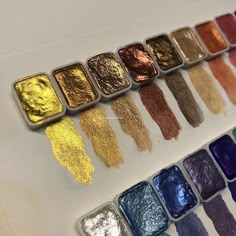 there are many different colors of paint in the box on the table, including gold and silver