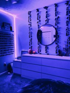 a room with purple lighting and a mirror on the wall next to a dresser in front of it