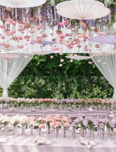 an outdoor wedding setup with umbrellas and flowers on the table, surrounded by greenery