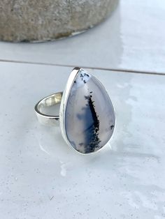 This Genuine Merlinite ring is suspended on a 925 Sterling Silver. Each ring is completely unique. They have been made to show off the very best patterns of the Dendritic Agate  This ring measures 25x18mm  Each piece of Jocale Jewellery comes in a beautiful box making it the ideal gift! Natural Merlinite  , Dendrite Agate , British, English Jewellery, English Jewelry, UK Jewellery, colourful jewellery, colorful Jewelry, pendant, Dendrite pendant, pedants, silver jewellery, unique jewellery, rare gemstone, English Jewellery, unusual jewellery, Unusual Gift, Christmas Gift **Note From Our Gemmologist- Marie Chalmers ** Merlinite is also know as Dendritic Agate. This is because it has plant like inclusions. When you look at it closely you will see it looks as if it has moss like plant growing Drop Shaped Cabochon Jewelry For Anniversary, Sterling Silver Cabochon Drop Jewelry, Agate Drop Gemstone Jewelry, Agate Gemstone Drop Jewelry, Drop Shaped Agate Gemstone Jewelry, Untreated Teardrop Silver Ring, Silver Agate Jewelry Hallmarked, Hallmarked Agate Jewelry For Anniversary, Anniversary Agate Jewelry Hallmarked