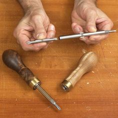 two hands holding tools on top of a wooden table with the words enlarge this image