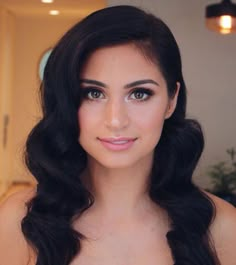 a woman with long black hair and blue eyes posing for a photo in front of a mirror