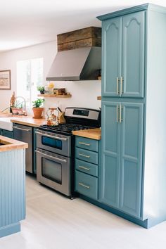 a kitchen with blue cabinets and stainless steel stove top oven in the center, surrounded by wooden counter tops