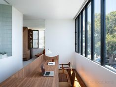 a laptop computer sitting on top of a wooden desk next to a window filled with lots of windows