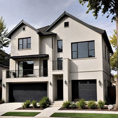 a two story white house with black garage doors