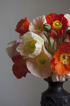 a black vase filled with lots of different colored flowers