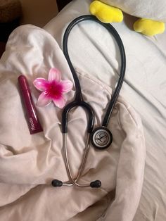 a stethoscope laying on top of a bed next to a pink flower