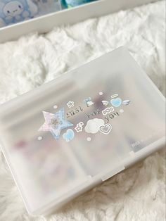 a clear plastic box with stickers on it sitting on top of a white blanket