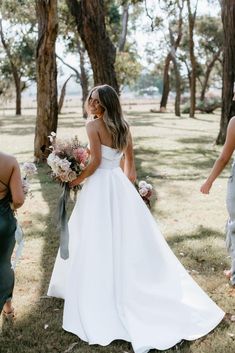 a woman in a white wedding dress standing next to two men