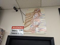 there is a painting on the wall next to a framed photo and a sign that says warning security cameras in use