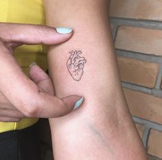 a woman's arm with a small heart tattoo on it