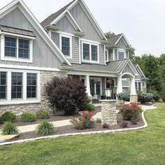 a large gray house with lots of windows and flowers in front of the entrance to it