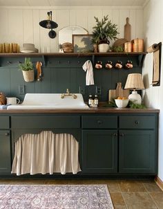 a kitchen with green cabinets and white counter tops on top of a rug in front of the sink