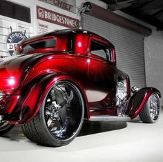 an antique red truck parked in front of a garage