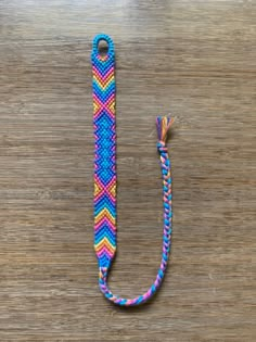 a blue, pink and yellow lanyard sitting on top of a wooden table