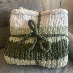 a green and white crocheted pillow sitting on top of a couch