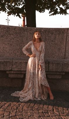 a woman in a long dress sitting on a stone bench