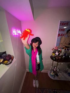 a woman standing in a room holding up a neon sign