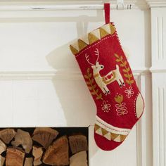 a red christmas stocking hanging from the side of a fireplace with logs in front of it