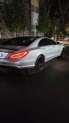 a silver car parked on the side of a road at night with its lights on