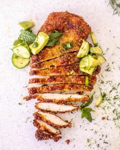 sliced chicken with cucumbers and herbs on a white surface, ready to be eaten