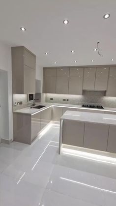 a large kitchen with white floors and counter tops in an open floor plan that is well lit by recessed lighting