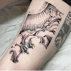 a black and white tattoo on the leg of a person with clouds in the sky