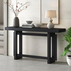 a black table with two vases and a lamp on it next to a potted plant