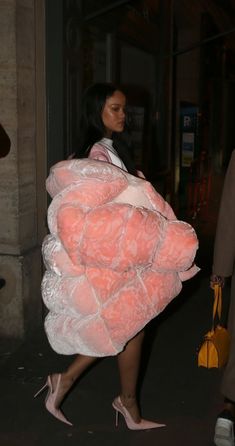 a woman walking down the street carrying a giant stuffed animal