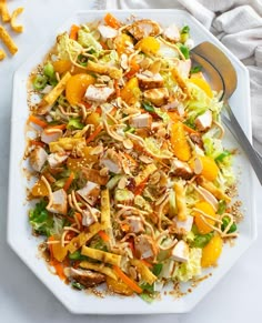 a white plate topped with salad next to a fork and knife on top of a table