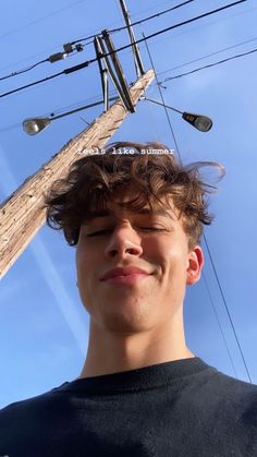 a young man standing under power lines with his head tilted to the side and eyes closed