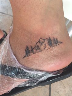 a foot with a mountain tattoo on it