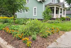 a green house with lots of flowers in the front yard