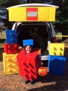 a young boy standing in front of a lego van