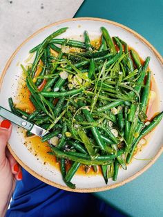 a person holding a plate with green beans on it