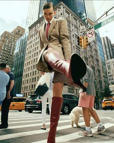 a woman in high heel boots is crossing the street with her legs up and feet down