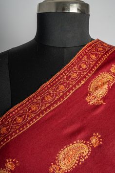 This deep red merino wool shawl features a stunning spread of Sozni hand-embroidered paisleys in golden hues, each pattern meticulously placed to showcase the masterful craftsmanship of Kashmiri artisans. The balanced use of intricate motifs against the bold red fabric lends an air of classic charm to the piece. Perfect for special occasions or as a statement wrap on chilly evenings, this shawl adds both warmth and sophistication to your look. The luxurious feel and exceptional embroidery make i Elegant Shawl With Embroidered Border For Traditional Ceremonies, Shawl With Motifs For Traditional Ceremonies, Festival Pashmina Shawl With Embroidered Border, Festive Ceremonial Shawl With Embroidered Border, Ceremonial Embroidered Jamawar Shawl, Ceremonial Shawl With Embroidered Border, Ceremonial Shawl With Embroidered Border And Traditional Drape, Embroidered Border Shawl For Traditional Ceremonies, Elegant Embroidered Pashmina Shawl For Traditional Ceremonies