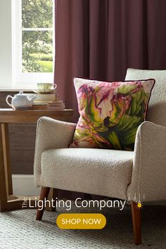 a chair with a pillow on it in front of a table and window sill