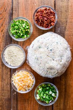 the ingredients for an appetizer laid out in bowls on a wooden table top