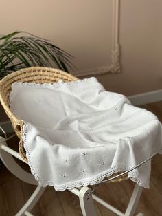 a baby's rocking chair with a white blanket on it and a potted plant in the background