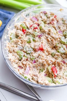 a bowl filled with tuna salad on top of a table next to utensils