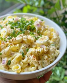 a white bowl filled with macaroni salad on top of a table next to a window