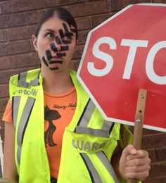 a woman holding a stop sign painted on her face