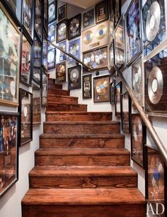 there is a staircase with many pictures on the wall and wooden steps that lead up to it