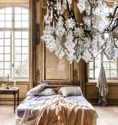 a chandelier hanging from the ceiling in a bedroom with a bed and table