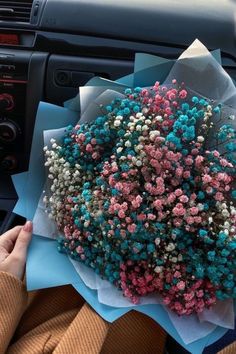 a person is holding a bouquet of flowers in their hand while sitting in the driver's seat of a car